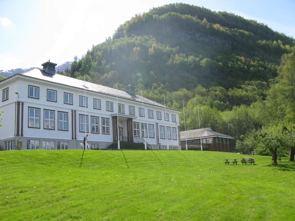 een groot wit gebouw met een heuvel op de achtergrond bij Hardanger Hostel B&B in Lofthus
