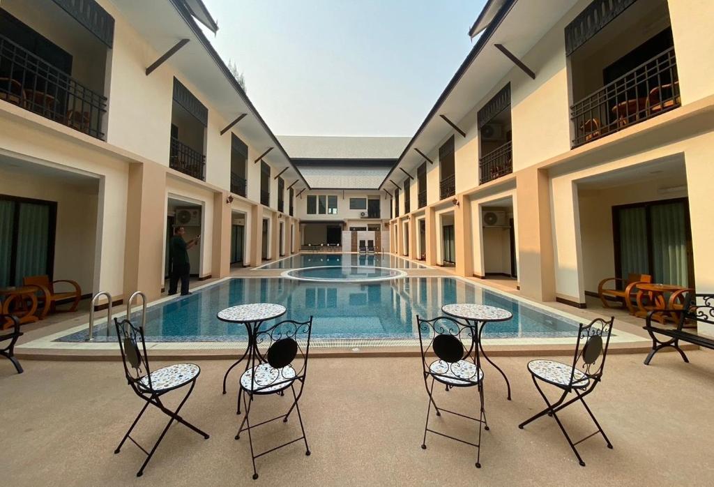 a pool with chairs and tables in front of a building at Peacock De Pai Hotel in Pai