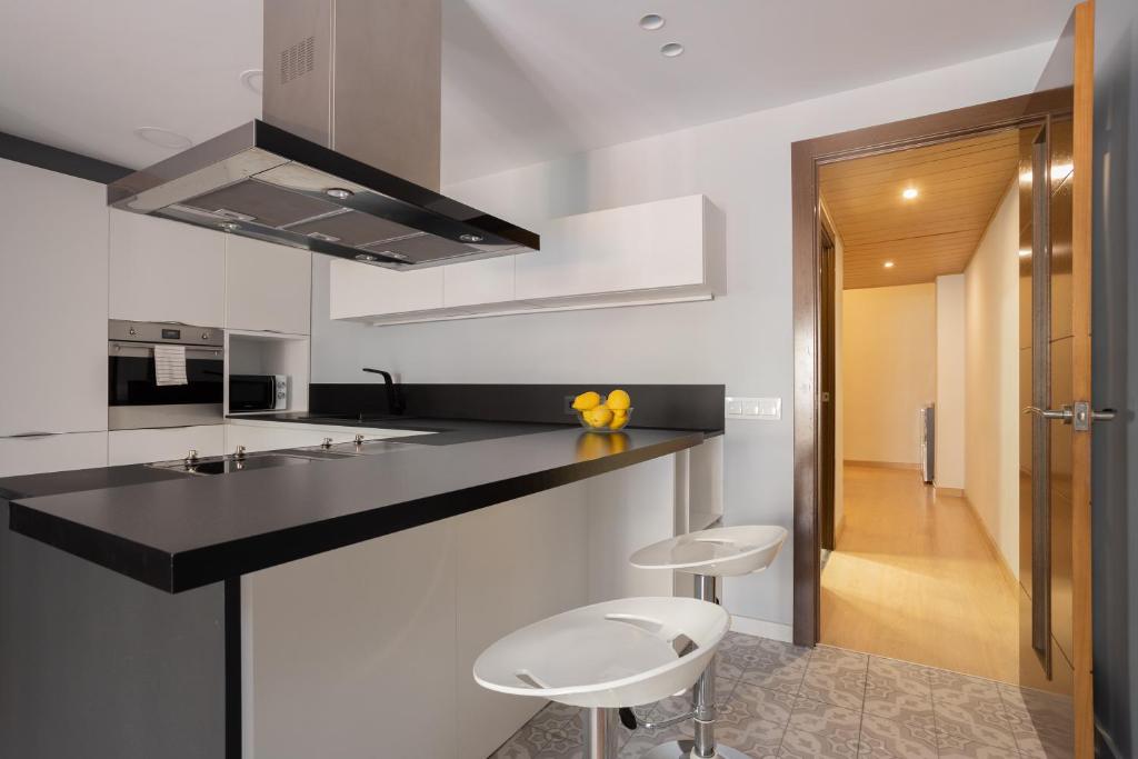 a kitchen with a black counter and two stools at Sunny Beachside Haven 2 Bd In The Marina District in Barcelona