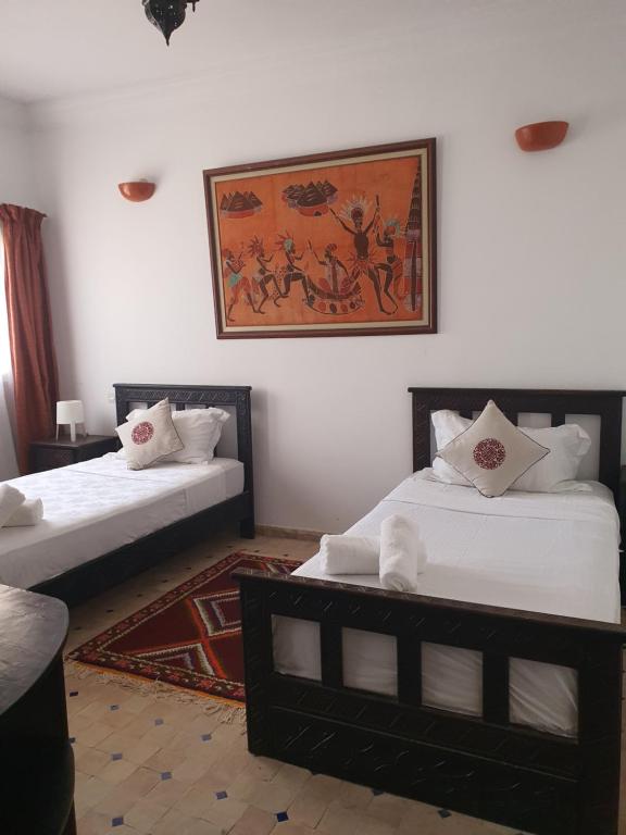 2 Betten in einem Zimmer mit Wandgemälde in der Unterkunft AZAWAN HOUSE in Tamraght Ouzdar