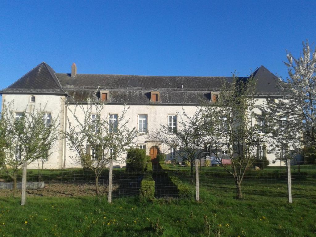 een groot wit huis met bomen ervoor bij Le Chateau de Buchy in Buchy