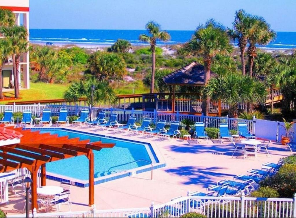 uma piscina de resort com cadeiras e a praia em Oasis 21 Oceanfront with Pool em Saint Augustine