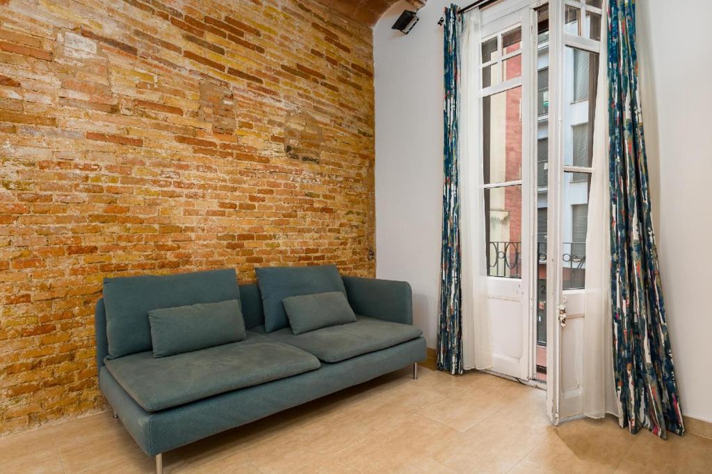 a living room with a couch and a brick wall at Gracia Gem Ac, Near Fontana Metro, Hipster Haven in Barcelona