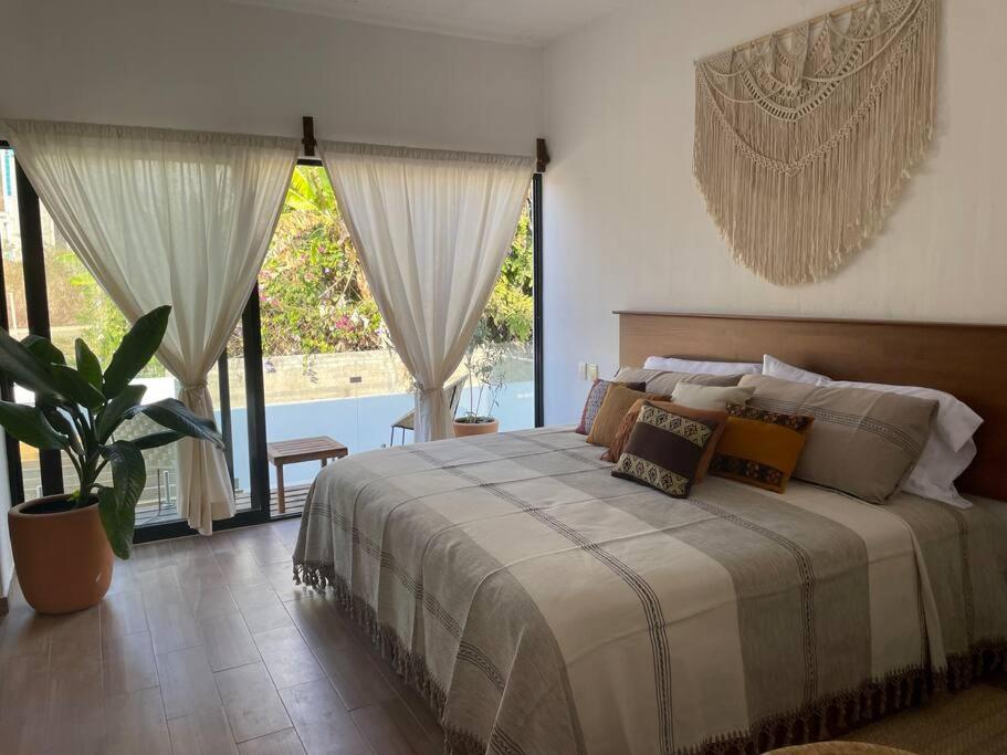 a bedroom with a bed and a large window at Casa Tres Iguanas, La Punta in Puerto Escondido