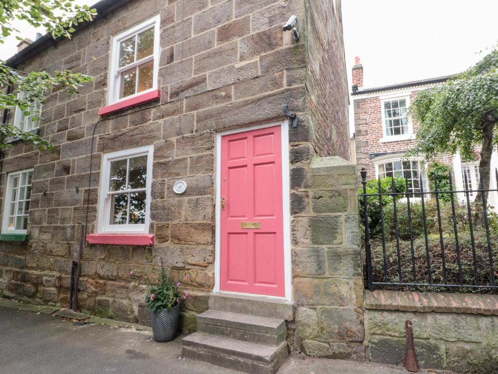 a red door on the side of a brick house at Red Grouse Cottage in Guisborough