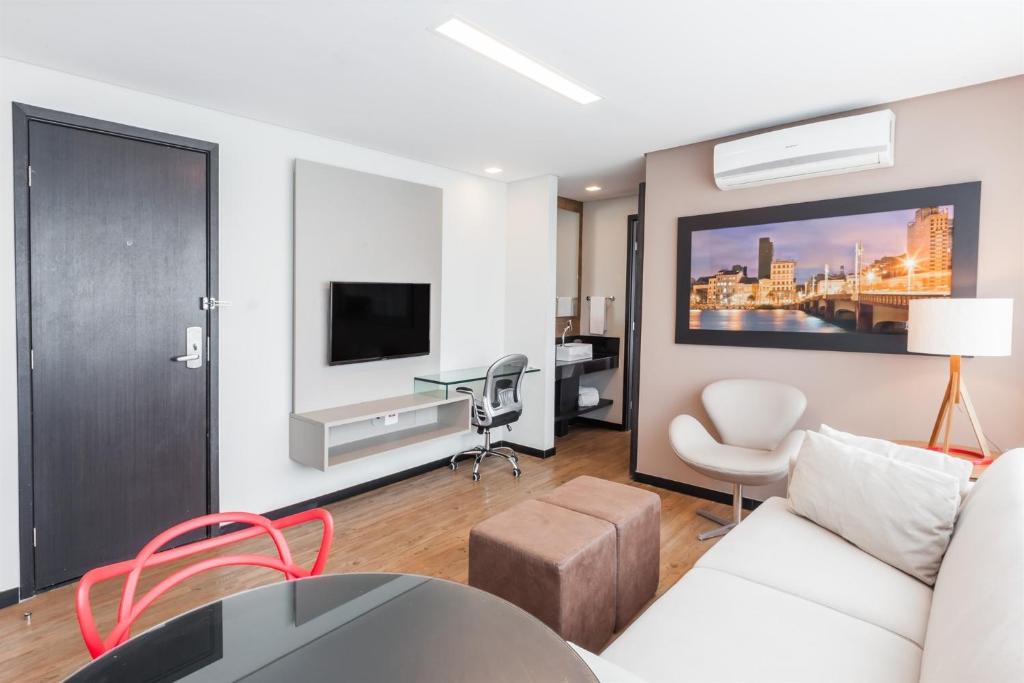 a living room with a white couch and a tv at Roomo Praia de Boa Viagem Residencial in Recife