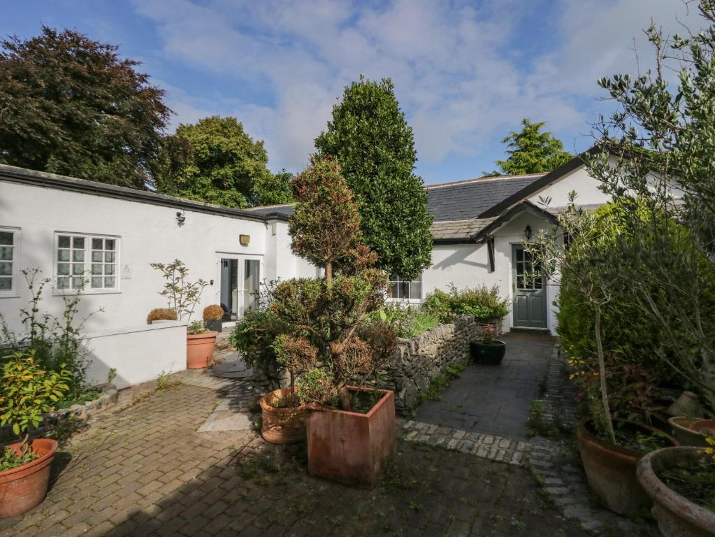 a white house with potted plants in front of it at Clarence House in Dalton in Furness