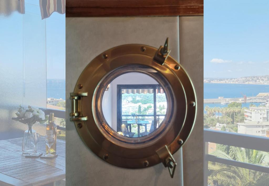 a round mirror on a wall in a room with a window at Nestor&amp;Jeeves - HUBLOT TERRASSE - Sea view - swimming pool in Nice
