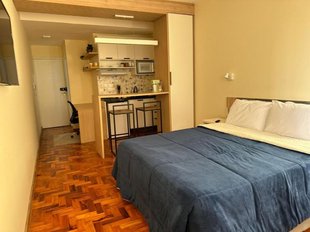 um pequeno quarto com uma cama e uma cozinha em Prédio central com apartamentos reformados em São Paulo