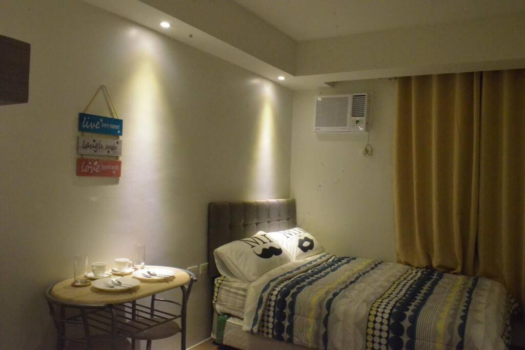 a bedroom with a bed and a table with glasses on it at Cozy Studio with Beautiful View & FREE Netflix Access in Manila
