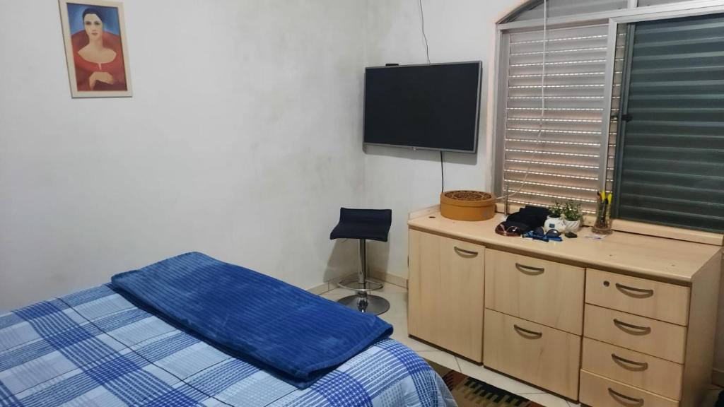 a bedroom with a bed and a dresser and a flat screen tv at Casa do Roberto in Jaraguá do Sul