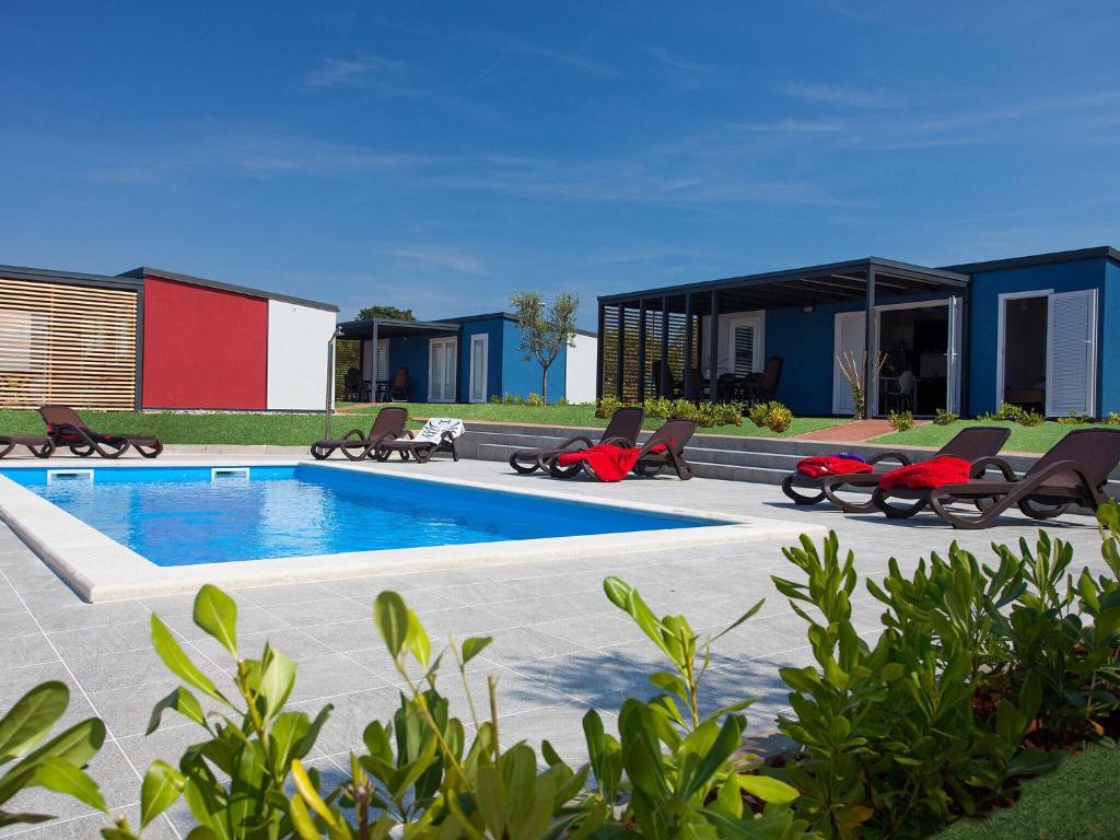 諾維格勒半島的住宿－Modern chalet with 2 bathrooms and a veranda 16km from Umag，一个带椅子的游泳池以及一座房子