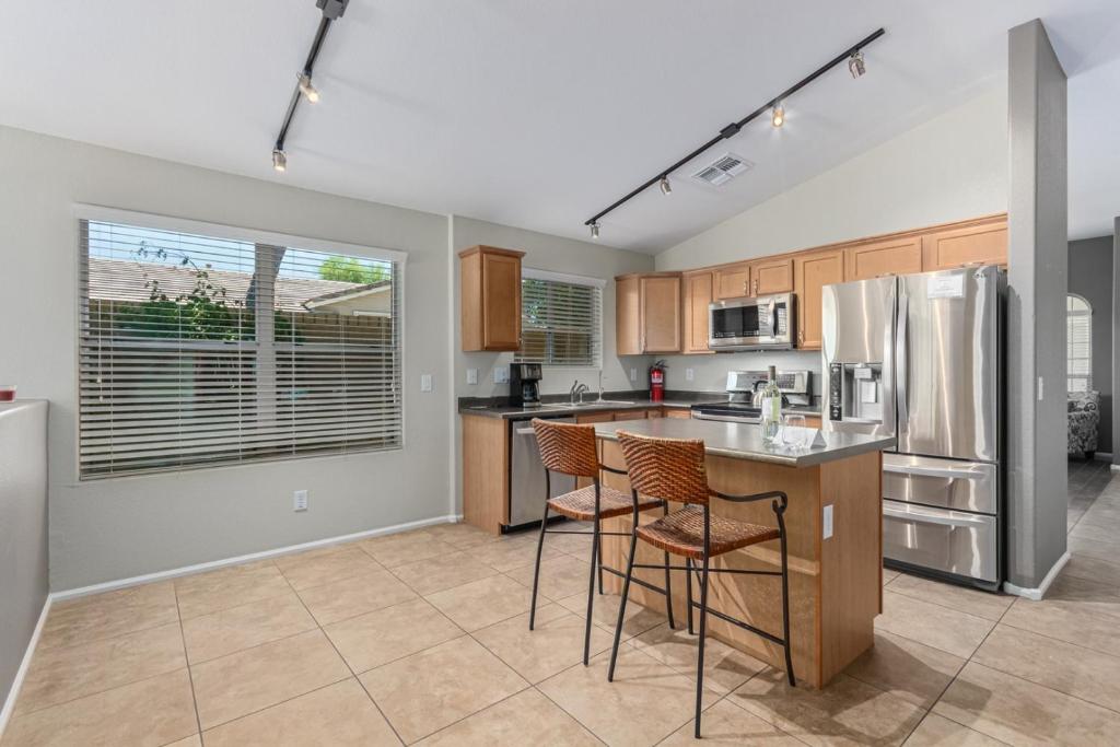 a kitchen with a counter and chairs and a refrigerator at Serenity Haven with Private Pool in Gilbert in Queen Creek