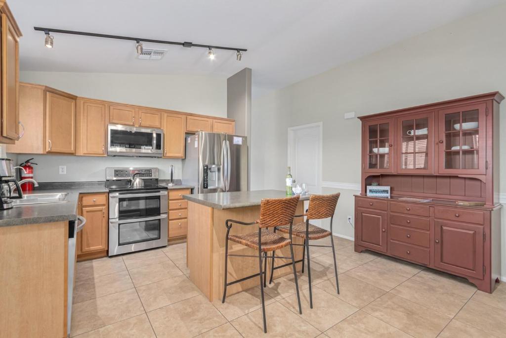 a kitchen with wooden cabinets and a kitchen island with stools at Serenity Haven with Private Pool in Gilbert in Queen Creek