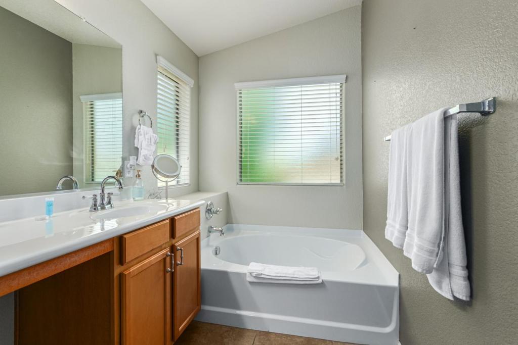 a bathroom with a tub and a sink and a mirror at Serenity Haven with Private Pool in Gilbert in Queen Creek