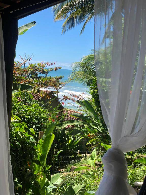 um quarto com uma janela com vista para a praia em Chalé Tiririca pé na areia em Itacaré