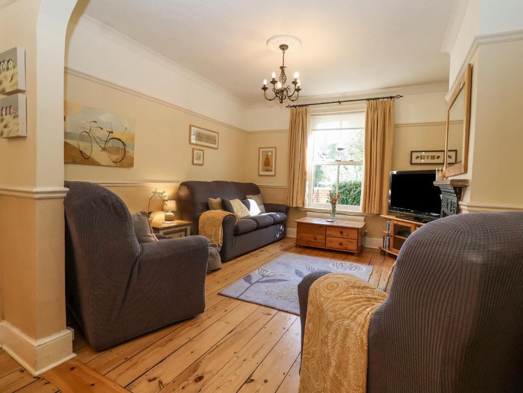 a living room with a couch and a tv at Green Gate Cottage in Southwold