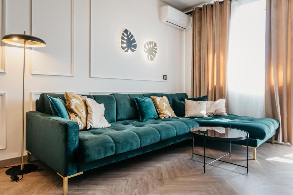 salon z zieloną kanapą i stołem w obiekcie Nocosfera Apartament Premium Ogrodowy II w Kaliszu