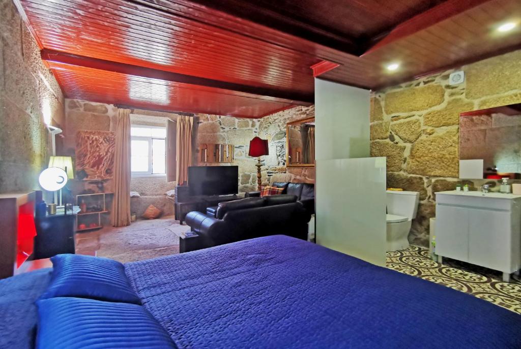 Un dormitorio con una cama azul y una pared de piedra en ROSA XVI - Garden Guest House, en Vilar Torpim