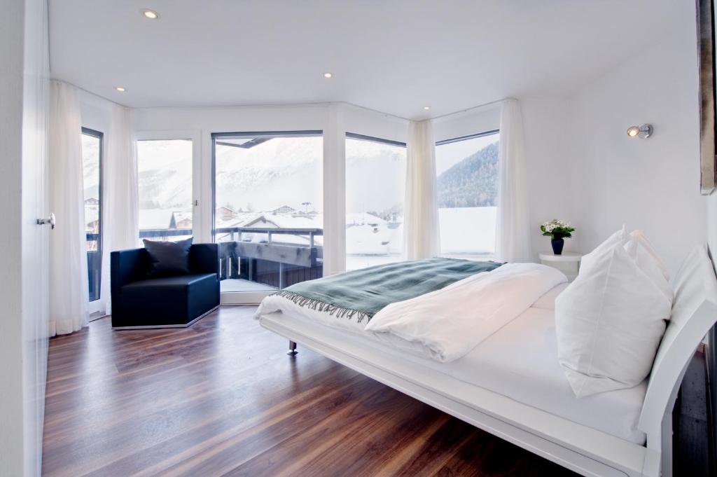 um quarto branco com uma cama e uma cadeira em Haus Allegra em Saas-Fee