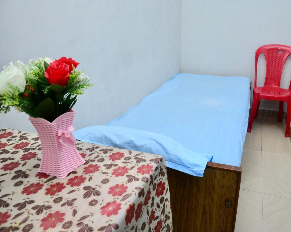 a room with a bed and a table with a vase of flowers at Namaskar Lodge and Homestay in Guwahati