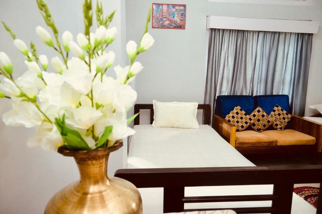 a living room with a couch and a vase with white flowers at Namaskar Lodge and Homestay in Guwahati