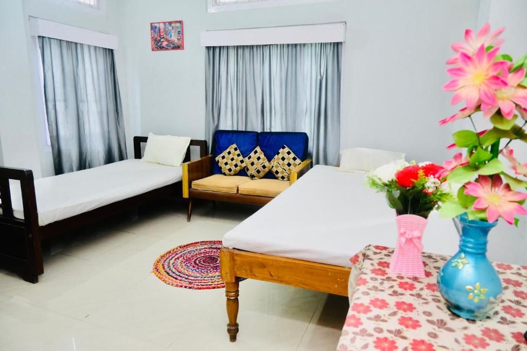a living room with a couch and a table with flowers at Namaskar Lodge and Homestay in Guwahati