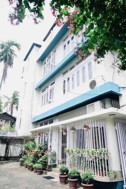 a white building with potted plants in front of it at Namaskar Lodge and Homestay in Guwahati