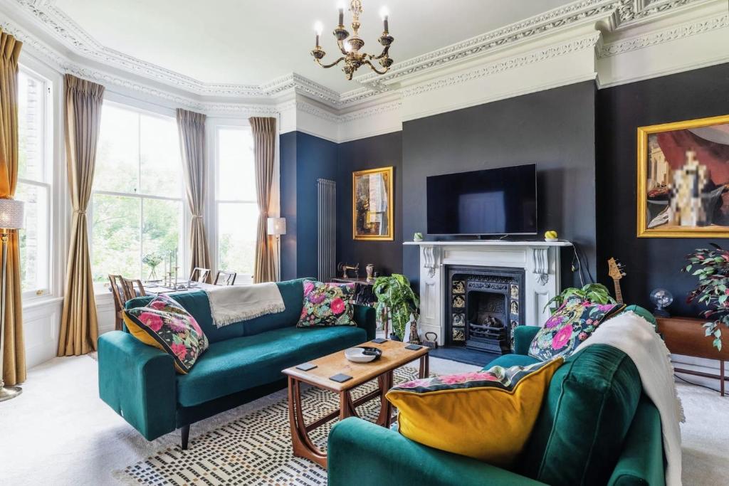 a living room with two green couches and a fireplace at Charming 1 Bed London Flat in London
