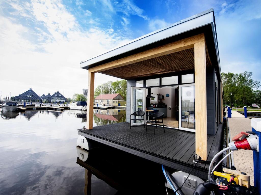 uma pequena casa em um barco em um corpo de água em Modern houseboat top location with an unobstructed view of the Lake em Offingawier
