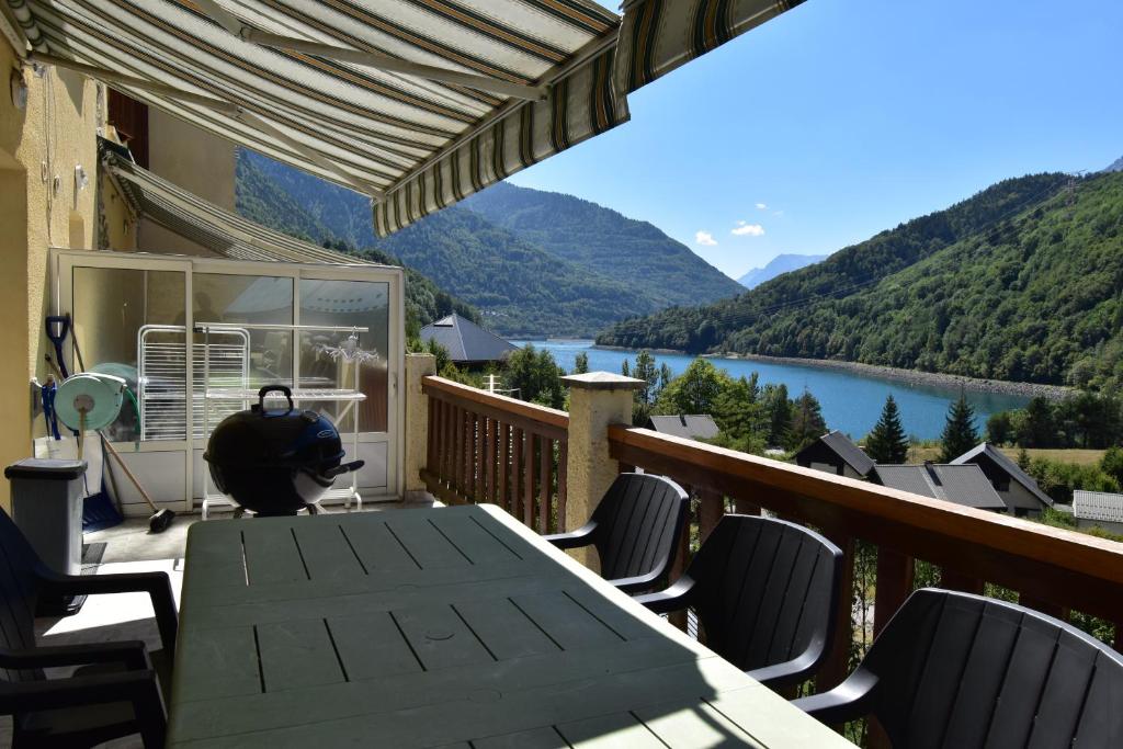 a deck with a table and chairs and a view of a lake at VAUJANYLOCATIONS - Roches Grandes 49 in Vaujany