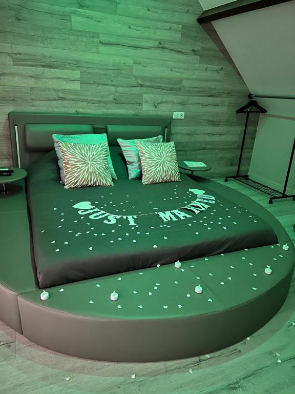 a bed with a green comforter with white flowers on it at Chambre privatif spa in Lestrem