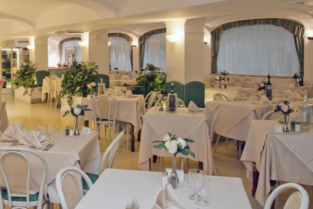 um salão de banquetes com mesas e cadeiras brancas em Hotel Solemare Beach & Beauty SPA em Ischia