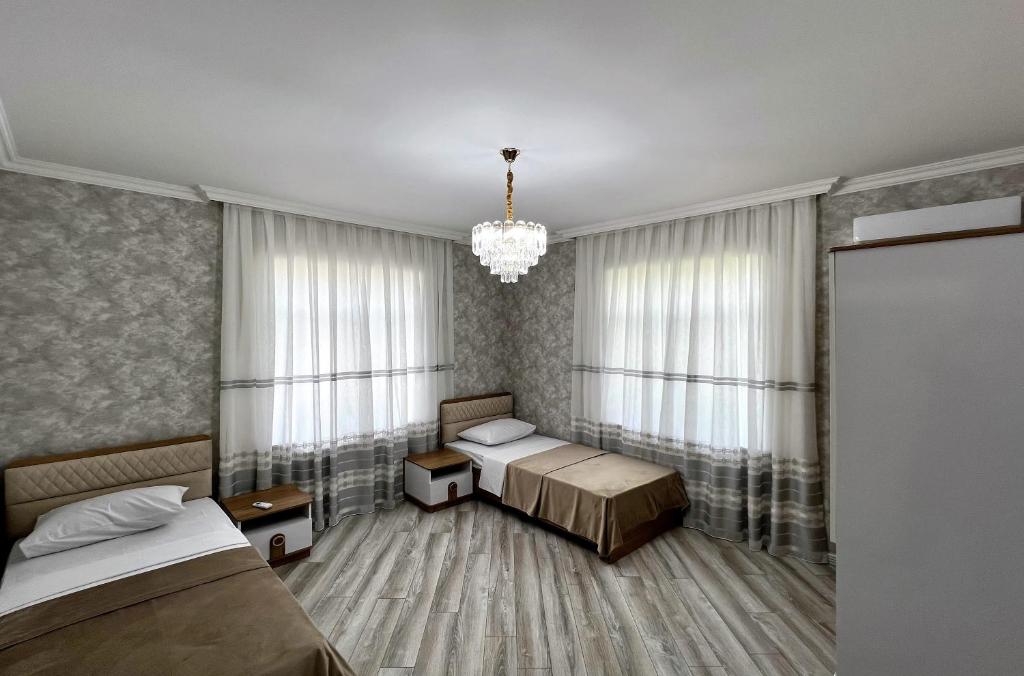 a bedroom with two beds and a chandelier at Qafqaz Manor Napoli in Gabala