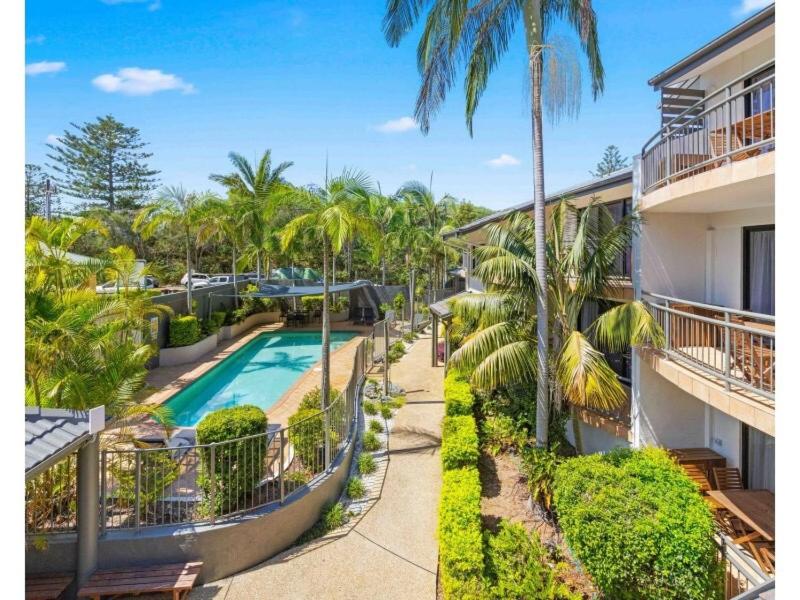 ariaal uitzicht op een resort met een zwembad en palmbomen bij Beachfront Apartments in Port Macquarie