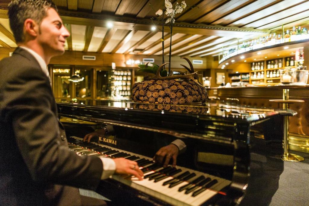 a man playing a keyboard in a bar at Hotel Alpenroyal - The Leading Hotels of the World in Selva di Val Gardena