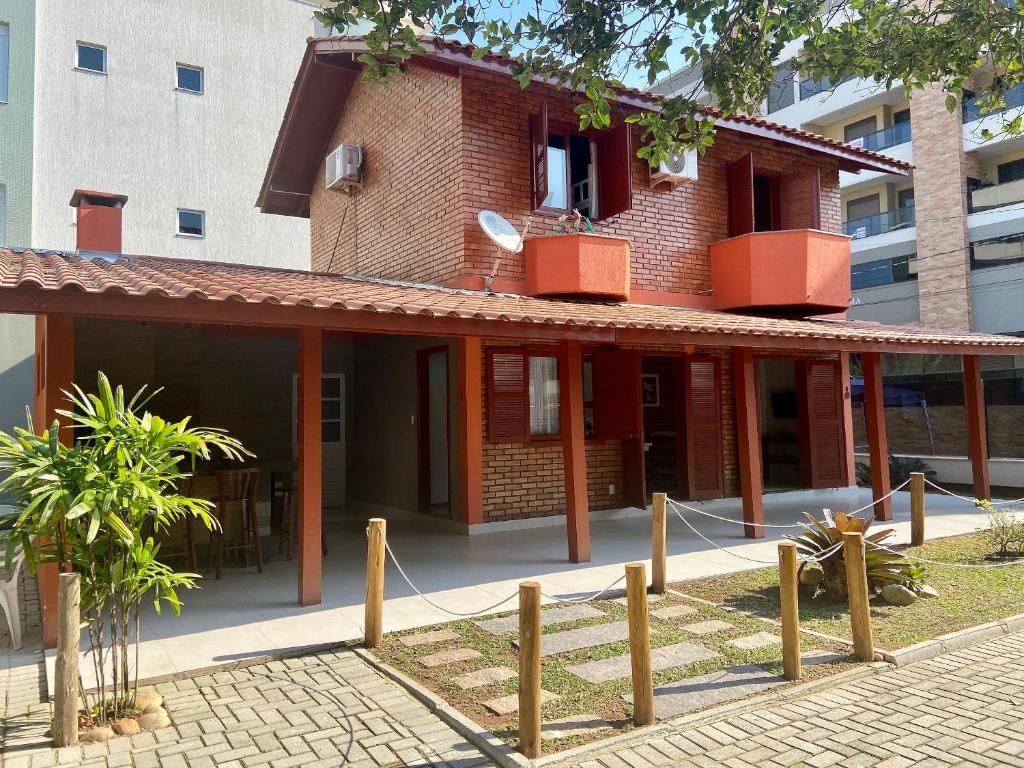 ein Backsteingebäude mit einem Zaun davor in der Unterkunft 020A - Sobrado de 3 quartos para alugar, Bombinhas/SC in Bombinhas