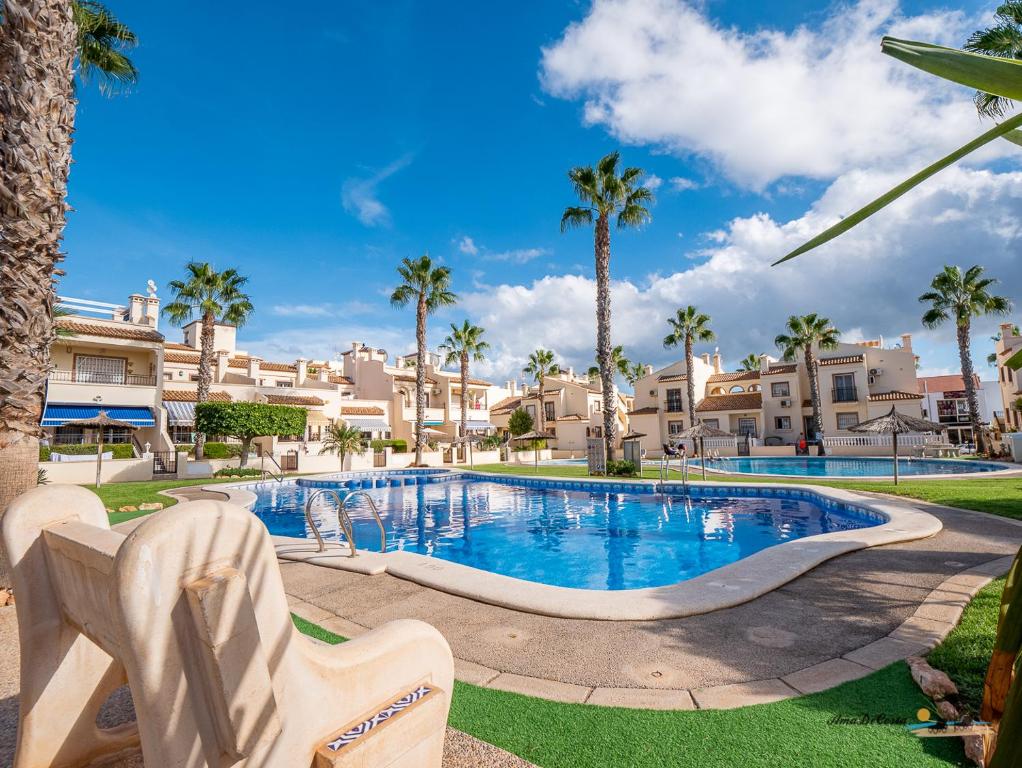 a large swimming pool with palm trees and houses at CASA DE FLAMENCO in Orihuela Costa