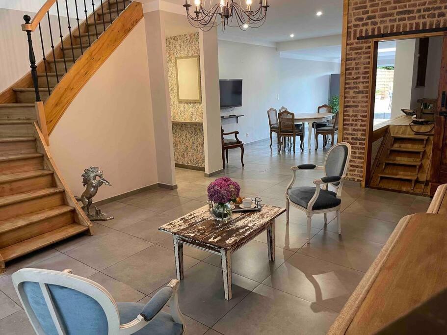 sala de estar con mesa y sillas y escalera en La maison de Solange, en Esquelbecq