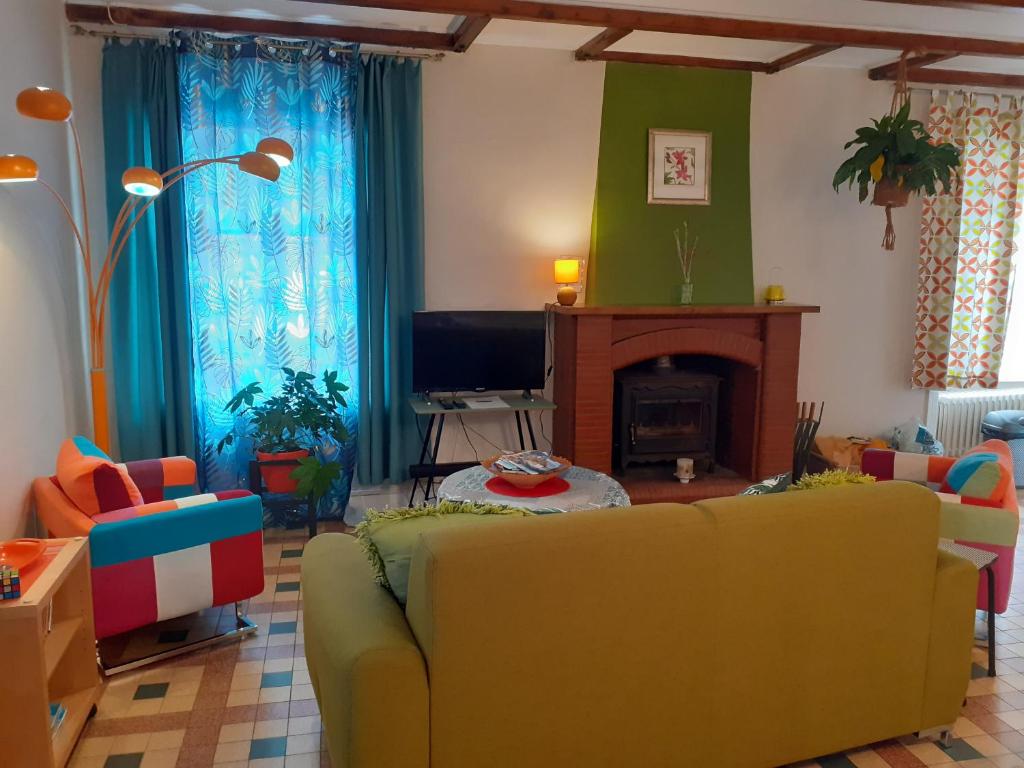 sala de estar con sofá amarillo y chimenea en Rêve du Revert, en Roz-sur-Couesnon