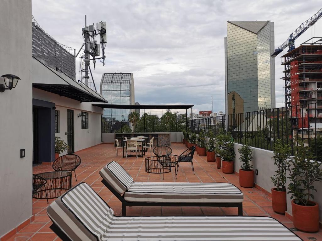 eine Terrasse mit Tischen und Stühlen auf dem Balkon in der Unterkunft Ihost Chapultepec @Serra in Guadalajara