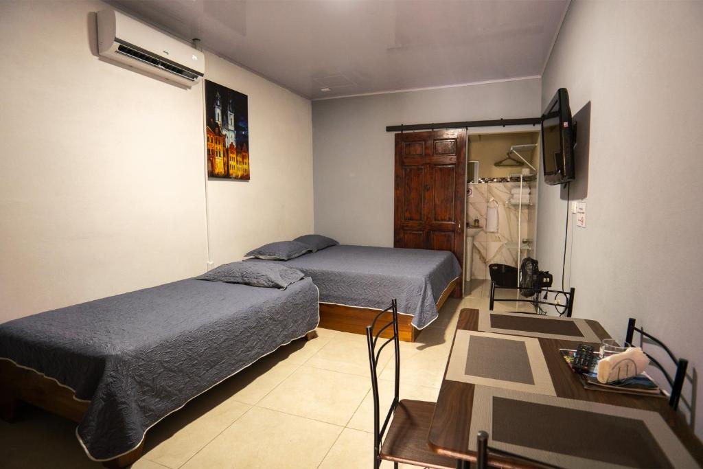 a bedroom with two beds and a table and a television at Apartamento Quepoa in Quepos