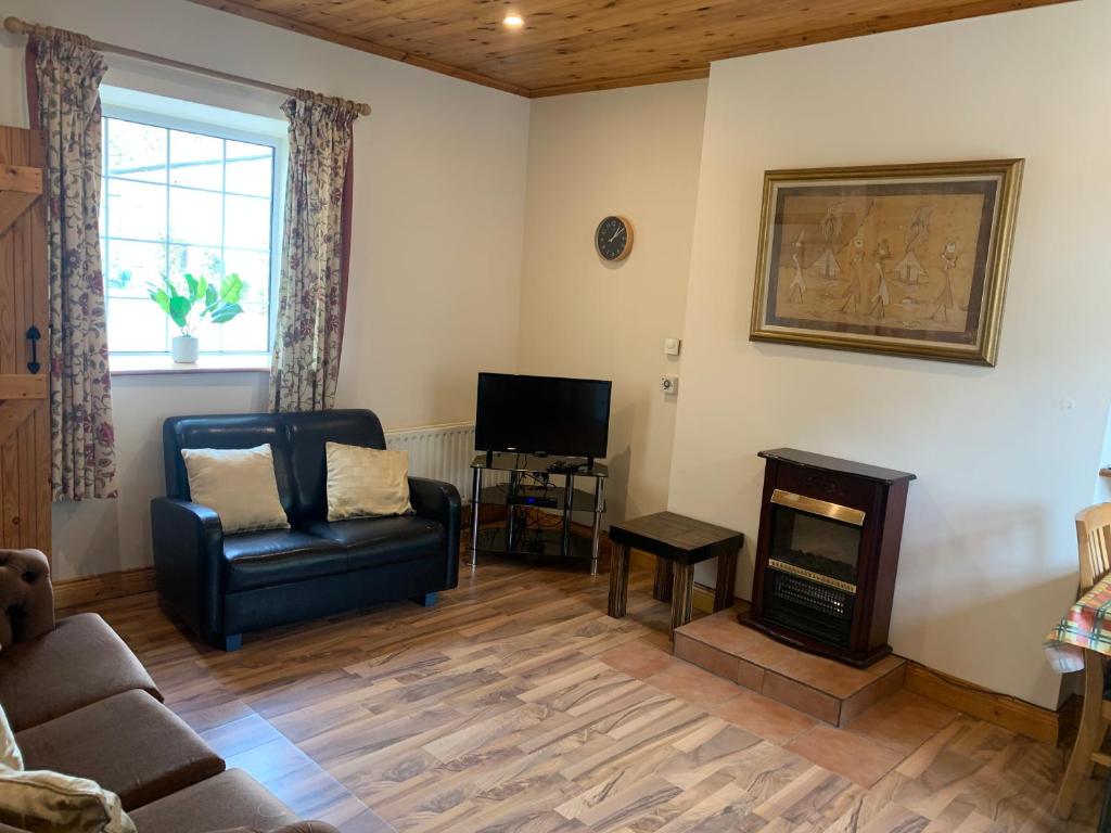 uma sala de estar com um sofá e uma cadeira e uma televisão em Castlehamilton Mill Cottage em Killashandra