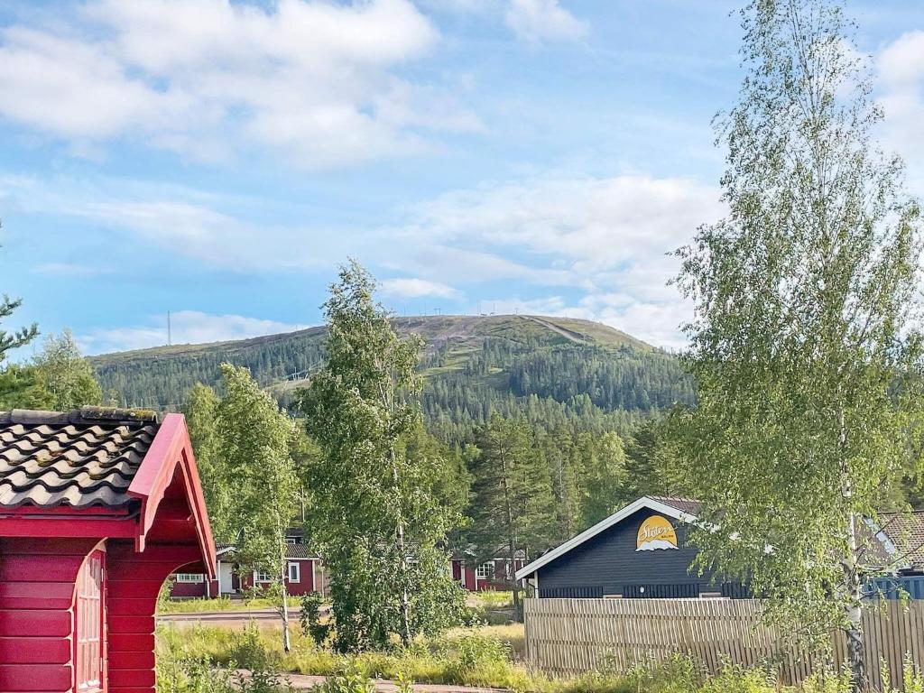 a red barn and a blue building with a mountain in the background at Holiday home SÄLEN XXIX in Stöten
