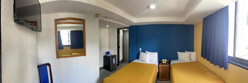 Habitación con 2 camas y pared azul en Hotel Renovación, en Caracas