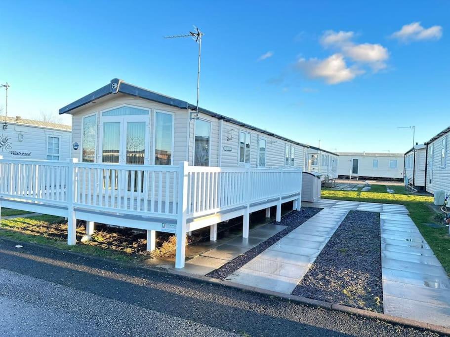 a mobile home with a porch and white railing at 8 berth pet friendly caravan Lyons Robin Hood in Meliden