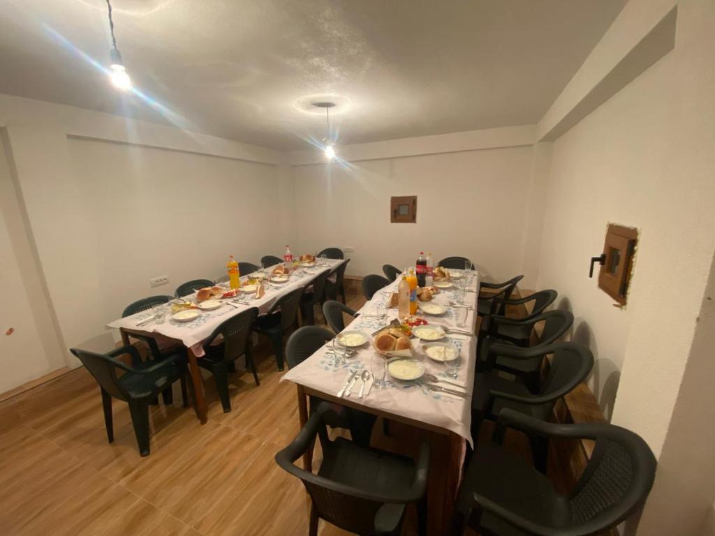 uma sala com mesas longas e cadeiras com comida em Shpija e Gjyshit Vuthaj em Gusinje