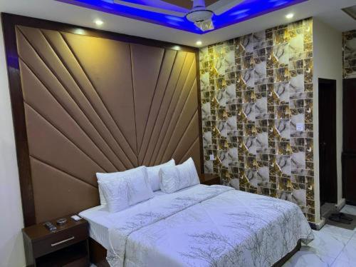 Un dormitorio con una cama grande y una pared con azulejos. en Defence Orchard DHA Karachi en Karachi
