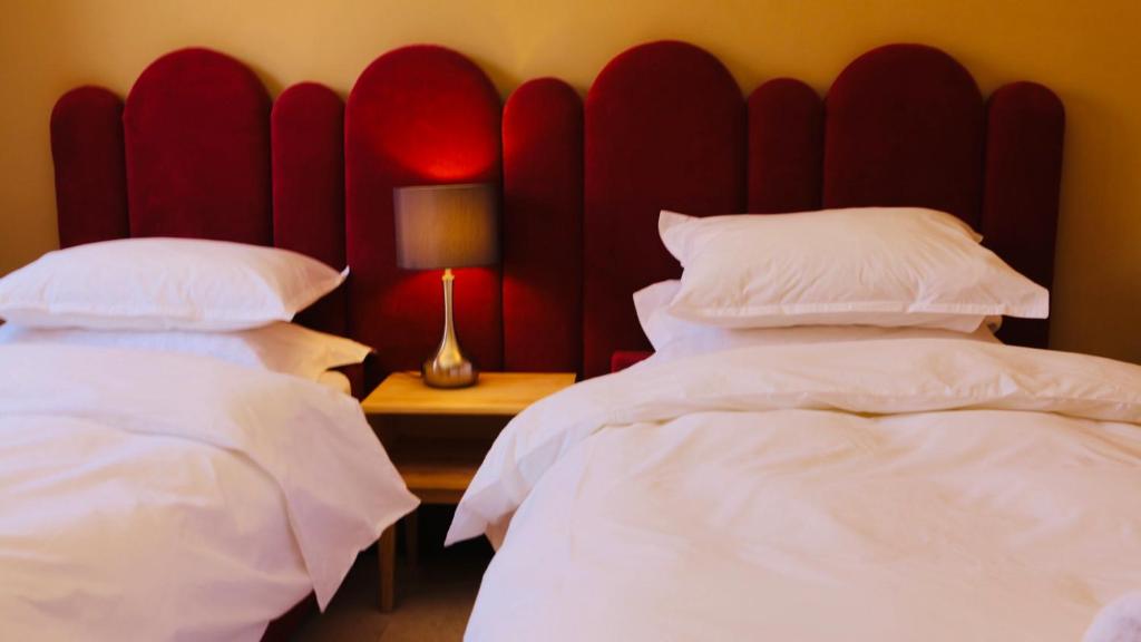 - une chambre avec 2 lits et une tête de lit rouge dans l'établissement Dar Guéliz, à Marrakech