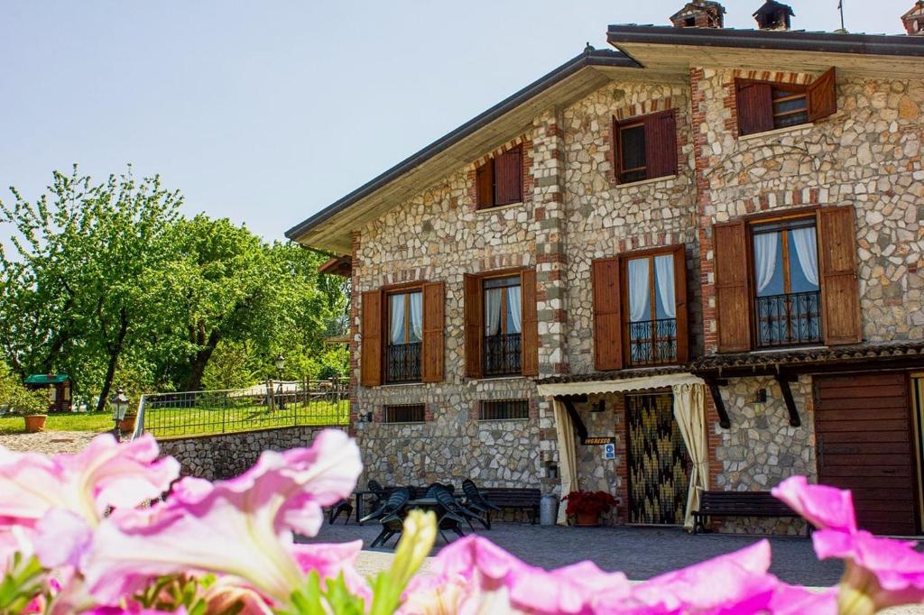 a large stone building with windows and pink flowers at Agriturismo Il Castagneto in Supino